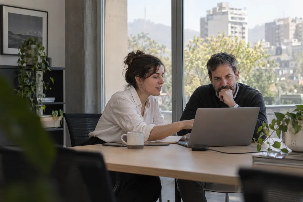 Dos profesionales colaboran frente a un computador con luz natural